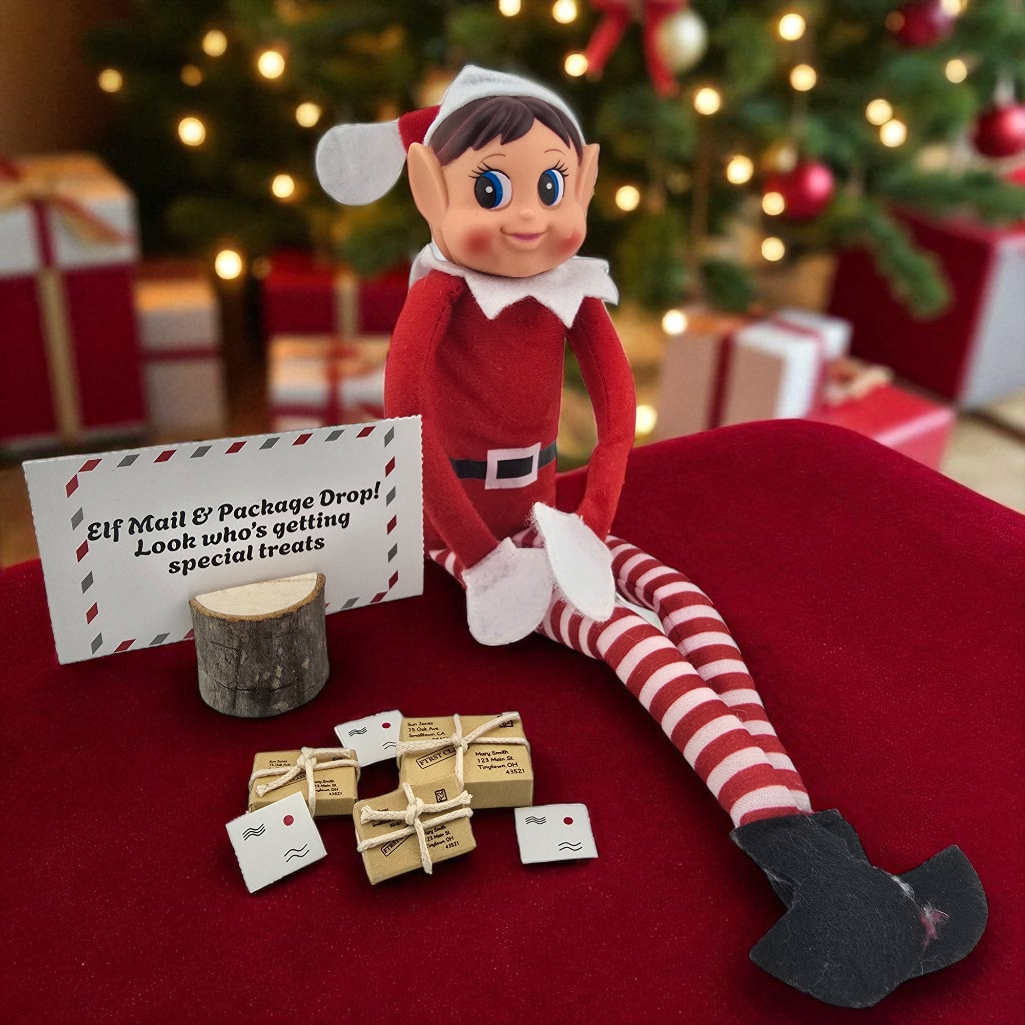 Christmas elf doll sitting next to miniature mail envelopes and tiny tied package props from the 24 day elf kit.