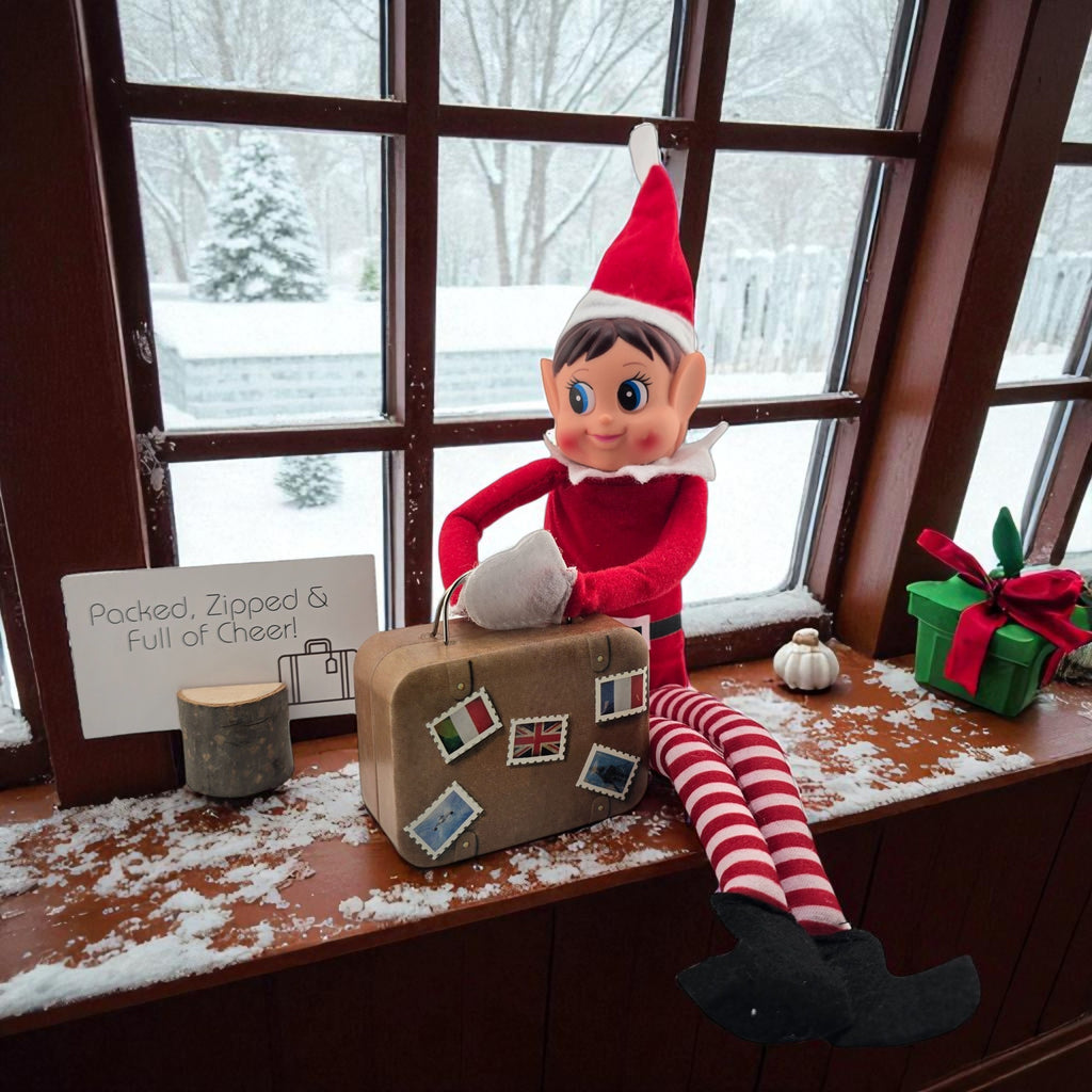 Christmas elf doll sitting on a windowsill with a miniature vintage suitcase prop from the 24 day elf kit.